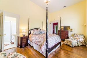 a bedroom with a four poster bed and a chair at Bourbon Manor Bed & Breakfast Inn in Bardstown