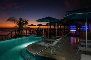 a swimming pool with chairs and umbrellas at a resort at Fort Young Hotel in Roseau