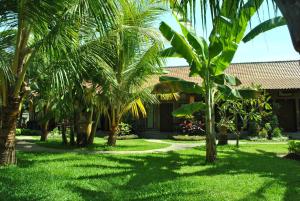 a yard with palm trees in front of a house at Pondok Rahayu Guest House in Pemuteran