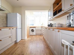 a kitchen with white cabinets and a washer and dryer at Seawynds in Newquay