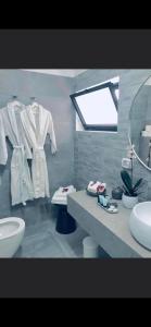 een badkamer met een wastafel en een aanrecht met witte badjassen bij בלקוני לחוף דור in Dor