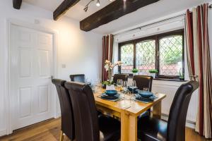 a dining room with a wooden table and black chairs at Sunshine Cottage by Happy Sunshine Stay in Golborne