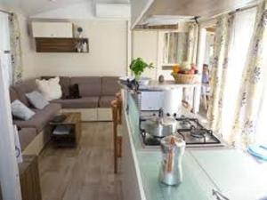 - une cuisine avec une cuisinière et un canapé dans la chambre dans l'établissement MOBIL HOME CAMPING LES SABLES DU MIDI, à Valras-Plage