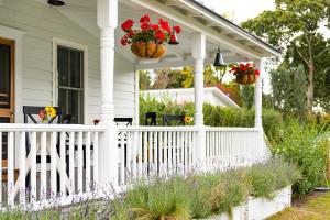 a white porch with red geraniums in baskets at Seven - a boutique B&B on Shelter Island in Shelter Island