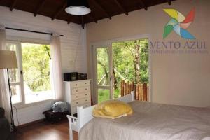 a bedroom with a bed with a yellow pillow on it at Casa LINDA TÉRREA e SUPER ACONCHEGANTE 3 Suítes in Camanducaia