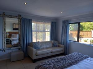 a living room with a couch and a mirror at Sola Fide Self Catering Apartment in Jeffreys Bay