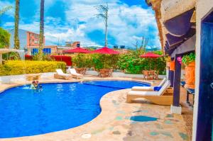 una piscina con sillas y sombrillas en un hotel en Hotel Casona del Virrey, en Moniquirá