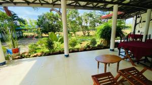 a porch with a table and chairs and a view of a park at Owin Rose Yala Safari Hotel in Tissamaharama
