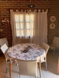 mesa de comedor con sillas blancas y ventana en Casa Mali en Azul