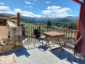 una mesa y sillas en un balcón con montañas en Casa Rural Alta Ladera, en Hoyos del Espino