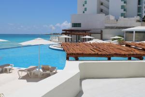 un complexe avec une piscine, des chaises et l'océan dans l'établissement Cyan Cancun Resort & Spa, à Cancún
