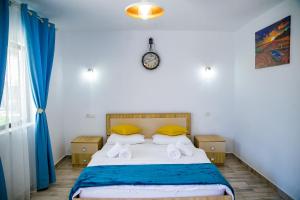 een slaapkamer met een bed met gele kussens en een klok bij Casa ERICKA in Vama Veche