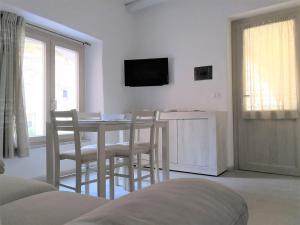 ein Wohnzimmer mit einem Tisch, Stühlen und einem TV in der Unterkunft Domu Antiga in Tertenìa