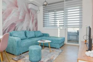 - un salon avec un canapé bleu et une table dans l'établissement Apartmani Martenovic 1, à Vrnjačka Banja