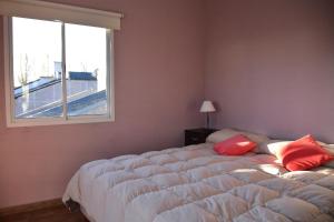 - une chambre avec un grand lit et des oreillers rouges dans l'établissement Presidencia Departamentos, à Tupungato