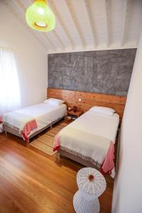 a bedroom with two beds and a stone wall at Adega Baía Azul - The essence of Pico in São Roque do Pico