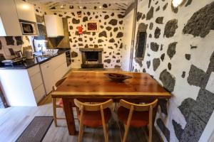 a kitchen with a wooden table and a stone wall at Adega Baía Azul - The essence of Pico in São Roque do Pico