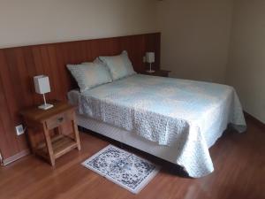 Casa MARAVILHOSA com 4 Suítes em Condomínio في كاماندوكايا: غرفة نوم مع سرير وطاولتين مع مصابيح
