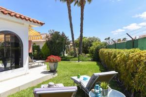 einen Garten mit Stühlen, einem Tisch und einem Haus in der Unterkunft Bungalow Sun Club EM259A by VillaGranCanaria in Playa del Ingles