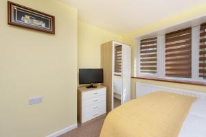 1 dormitorio con cama y vestidor con TV en Quest Fulfiller - Near hospital Free parking and Garden en Southampton