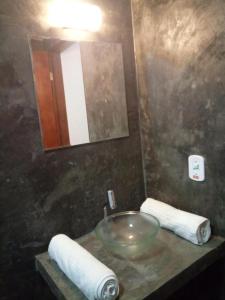 y baño con lavabo, espejo y toallas. en Pousada Tarkna, en Teresópolis