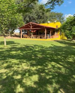 a yellow house with a large yard with a large shadow at Pousada Chalés Praia Vermelha in São João Batista do Glória