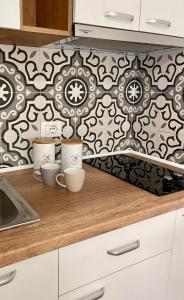 a kitchen counter with two cups and a wallpaper at SOL Lux Apartments 1st Floor in Durrës