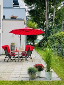 a patio with a table and chairs with red umbrellas at Lakeview Appartements in Zeuthen