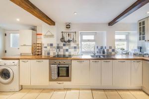 a kitchen with white cabinets and a washer and dryer at Pye Hall Cottage in Silverdale