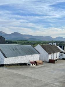 two large white buildings with mountains in the background at Maggie's Croft Cottages 4 Star Tourism NI in Castlewellan