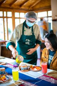 Um homem e uma mulher numa cozinha a preparar comida. em Unuwasi Hotel & Villa em Calca