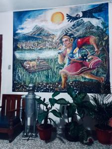 a painting on the wall of a room with plants at Hostal Chasqui in Otavalo