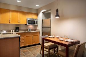 a kitchen with a wooden table with chairs and a kitchen with stainless steel appliances at Sonesta ES Suites Tempe in Tempe