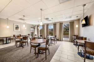 un comedor con mesas, sillas y ventanas en SureStay Hotel by Best Western SeaTac Airport North, en SeaTac