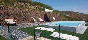 a swimming pool with chairs and a stone wall at Casa da Fraga in Santa Marta de Penaguião