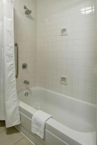 a white bathroom with a tub and a towel at Sonesta Select Milwaukee Brookfield in Brookfield
