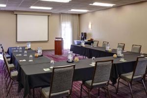 a conference room with tables and chairs and a screen at Sonesta Select Milwaukee Brookfield in Brookfield