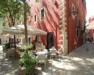 een patio met tafels en stoelen naast een rood gebouw bij Hotel Museu Llegendes de Girona in Girona