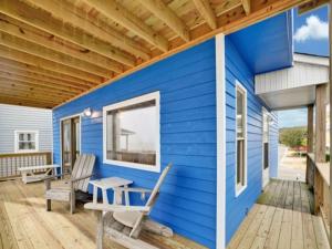 Una casa azul con dos sillas y una mesa en un porche. en Sea Haven - OCEANFRONT! Amazing master suite with a private oceanfront deck! Recently renovated and perfect for the entire family home, en Kure Beach