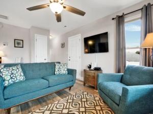 Una sala de estar con un sofá azul y dos sillas. en Sea Haven - OCEANFRONT! Amazing master suite with a private oceanfront deck! Recently renovated and perfect for the entire family home, en Kure Beach 27 fotos más