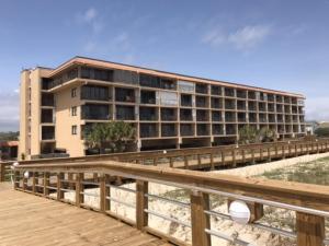 a large building on the beach next to a wooden boardwalk at Sea Life - OCEANFRONT! Pleasure Island Paradise! Lose yourself in the ocean views! condo in Carolina Beach