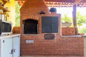 an outdoor brick oven in a kitchen with a counter at Pousada Chalés Praia Vermelha in São João Batista do Glória