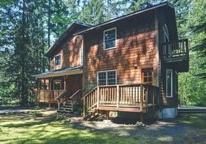 a log cabin with a porch and a deck at River Dance Retreat - Meredith Lodging in Welches