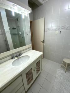 une salle de bain avec un lavabo et un miroir dans l'établissement Hermoso dpto con vista frontal al Mar Pitangueiras, à Guarujá