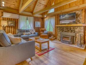 a living room with a stone fireplace and a tv at Storybrooks Cabin - Meredith Lodging in Rhododendron