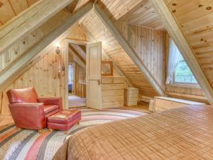 a attic bedroom with a bed and a chair at Storybrooks Cabin - Meredith Lodging in Rhododendron