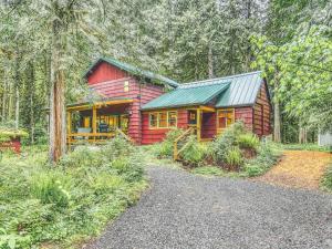 a red cabin with a green roof in the woods at Ripplewood - Meredith Lodging in Welches