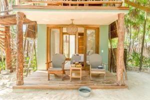 a home with a wooden porch with chairs and a table at Ahau Tulum in Tulum