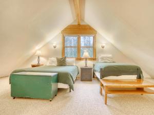 Un dormitorio abuhardillado con dos camas y una mesa. en Marshall Cabin - Meredith Lodging, en Government Camp