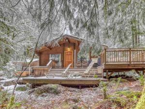 a log cabin in the woods with a porch and stairs at Moondance Cabin - Meredith Lodging in Rhododendron